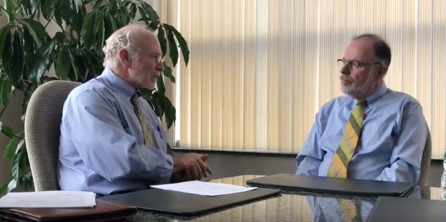 two businessmen talking at a desk